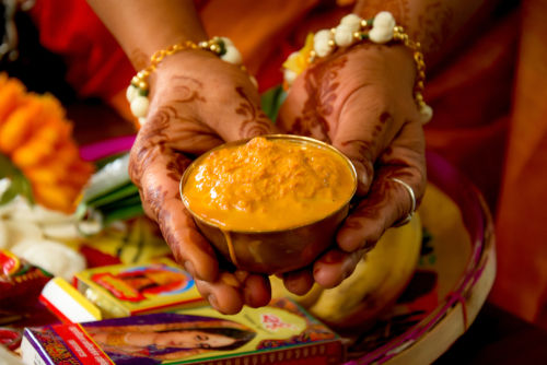 Eine Frau, die für ihre Hochzeitszeremonie eine Schüssel Kurkuma hält. Es handelt sich um Rituale der traditionellen Hindu-Hochzeit, die als Haldi-Zeremonie bekannt ist.