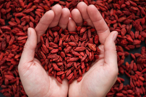 Rote getrocknete Goji-Beeren-Superfood-Draufsicht auf den Händen in Herzform