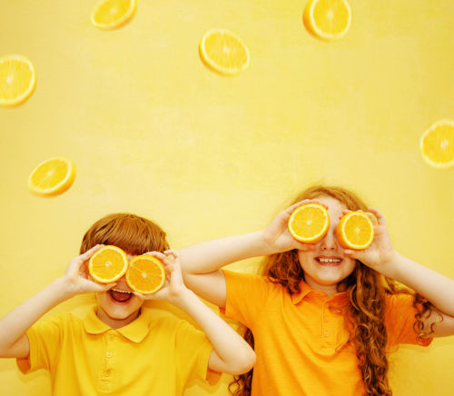 Lachende Kinder mit orangefarbenen Augen zeigen weiße gesunde Zähne auf einem gelben Hintergrund. Gesundheit, Lebensstil und eine glückliche Kindheit Konzept.